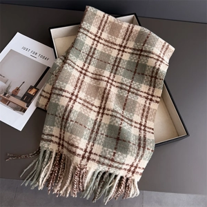 Détail de l'écharpe à carreaux avec pompons sur coffret cadeau avec texture cachemire