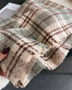Gros plan d'une écharpe en cachemire à carreaux avec pompons verts et tissu doux