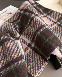 Gros plan montrant la texture épaisse en maille à carreaux et les franges de cette écharpe