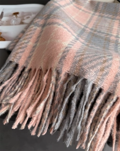 Détail de la texture de l'écharpe à carreaux avec franges douces roses et grises