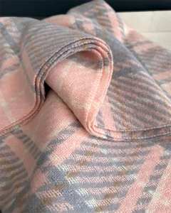 Gros plan d'une écharpe à carreaux rose et gris montrant le tissage doux