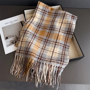 Détail d'une écharpe à carreaux et franges ginger et gris dans un coffret cadeau noir élégant