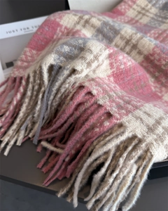 Gros plan d'une écharpe à carreaux rose et gris avec franges et maille épaisse