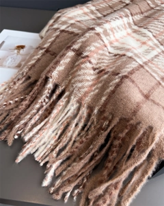 Gros plan de la texture de l'écharpe à carreaux marron avec tissage doux et franges