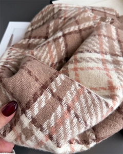Détail de la texture douce d'une écharpe à carreaux marron et rose avec toucher cachemire