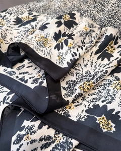 Detailed close-up of elegant silk-like fabric with French floral print in yellow and black