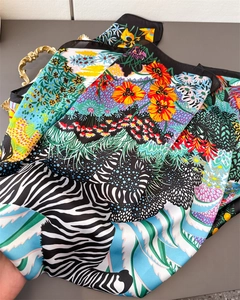 Detail shot of silk-like scarf featuring vibrant tropical flowers and zebra print textures