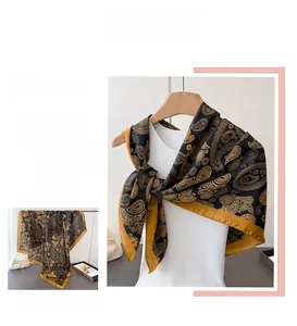 Detail des eleganten Paisleymusters in Schwarz und Gold auf dem Seidensatinschal