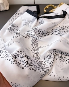 Close-up of silk-textured scarf with floral patterns and contrast black border detail