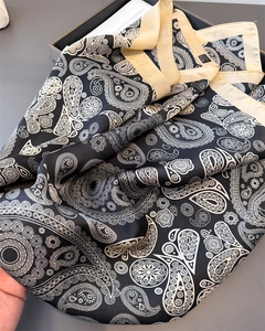 Detail eines Seidenschals mit schwarz-weißem Paisleymuster und elegantem cremefarbenem Rand