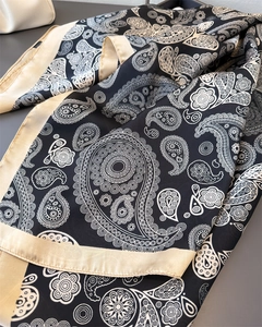 Detailansicht eines eleganten schwarzen Satintuchs mit goldenem Paisley-Muster