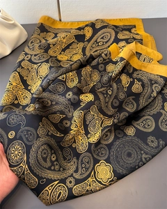 Detail eines Seidenschals mit goldenem Paisleuchtend goldenem Paisleymuster und gelber Bordüre