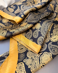 Detailaufnahme des Satin-Paisley-Schals mit edlen goldfarbenen Nähten und schwarzem Muster