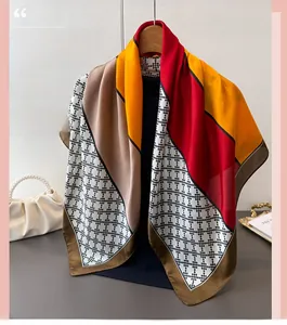 Detail of satin scarf featuring red and orange geometric patchwork on a wooden hanger