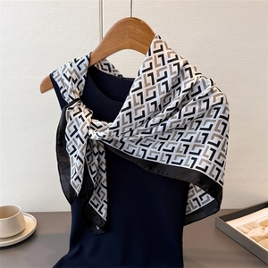 Detail view of vintage geometric pattern silk scarf draped on a black top and wooden hanger