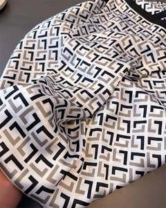 Close-up of vintage geometric pattern on silky satin scarf showing smooth glossy texture