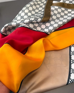 Close-up of luxury satin silk scarf featuring vibrant color-blocking and plaid border detail