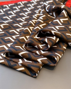 Close-up of geometric L-pattern satin scarf with red border showing silky texture