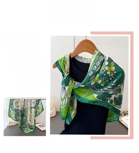 Detailed close-up of green clover silk scarf featuring floral prints and fine edge stitching