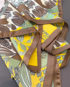 Detailed view of luxury clover print silk scarf showing smooth satin texture and floral pattern