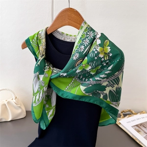 Artistic four-leaf clover floral silk scarf styled on a hanger with a pearl bag