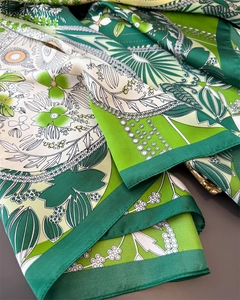 Close-up of silk-satin scarf with green four-leaf clover prints and paisley patterns
