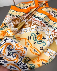 Macro detail of silky paisley print scarf with vibrant orange and yellow floral patterns