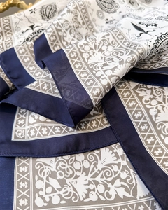 Close-up of silk-textured paisley square scarf with navy blue and grey panelled patterns
