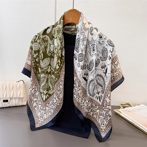 Detail of olive green and ivory paisley satin silk scarf on a wooden hanger with accessories