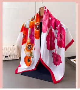 Vue détaillée d'un foulard en satin à fleurs orange et bordure rouge sur un cintre en bois