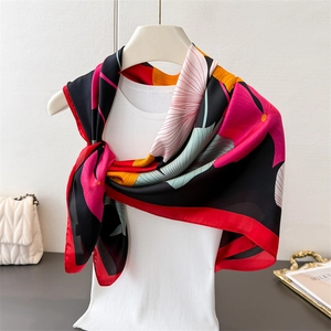 Detail eines bunten Satin-Halstuchs mit Ginkgo-Print, Blumenmuster und rotem Saum