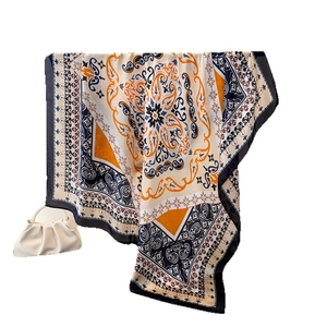 Bohemian paisley silk-like scarf in orange and navy blue shown with a stylish bag