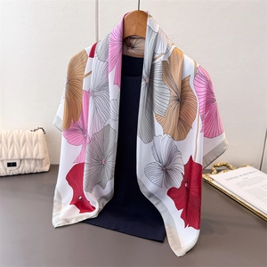 Detailansicht eines Seidensatin-Vierecktuchs mit Lotusmuster an einem Holzkleiderbügel