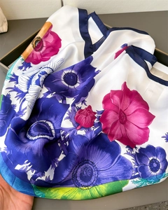 Détail d'un foulard en satin aux imprimés floraux violets et sarcelle avec bordure bleu marine