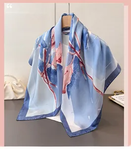 Detail of blue faux silk square scarf with pink floral patterns on a wooden hanger