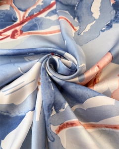 Detailed close-up of blue and red floral silk scarf showing glossy texture and drape