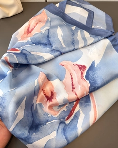 Close-up of silk-textured square scarf with abstract blue and pink watercolor floral patterns