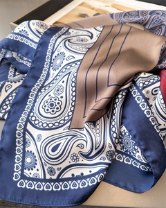 Detailed close-up of blue paisley satin scarf showing smooth texture and geometric print