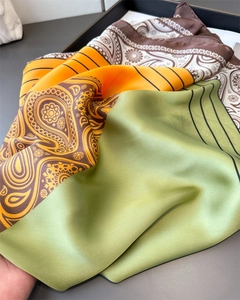 Detail of satin scarf showing green, orange, and brown paisley print and silky texture