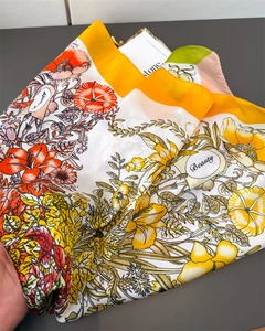 Detailopname van een zijden sjaal met oranje bloemenprint en zachte textuur