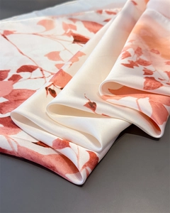 Detail of silk-like satin fabric with elegant orange floral print and subtle texture