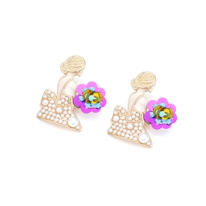 Détail de boucles d'oreilles silhouette fille dorée avec perles et perles colorées