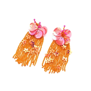 Detail of bohemian beaded tassel earrings with purple sequin flowers and orange fringe