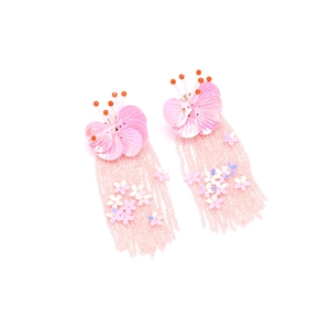 Macro detail of handmade bohemian pink sequin flower earrings with beaded tassel drops