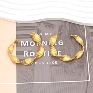 Gold twisted metal hoop earrings with brushed texture on a stylish magazine backdrop