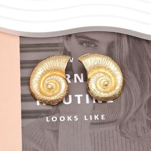 Golden spiral conch earrings with vintage nautilus shell design on a white wave tray