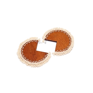 Bohemian style wood hoop earrings with off-white woven tassel trim on white background