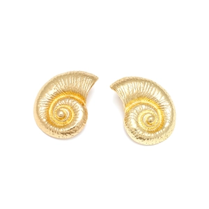 Macro detail of golden seashell earrings with spiral texture and metallic finish
