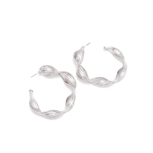 Macro shot of silver twisted C-shape hoop earrings with modern textured wave patterns