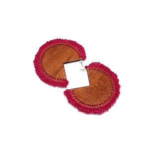 Detail of bohemian handmade wooden earrings with magenta crochet trim and silver studs